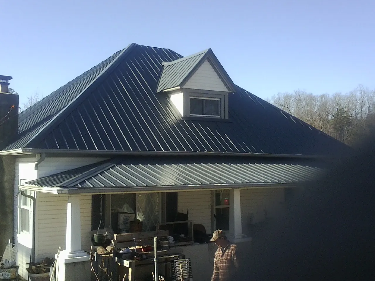 Dark blue standing seam metal roof with a dormer above a front porch in Dunnsville
