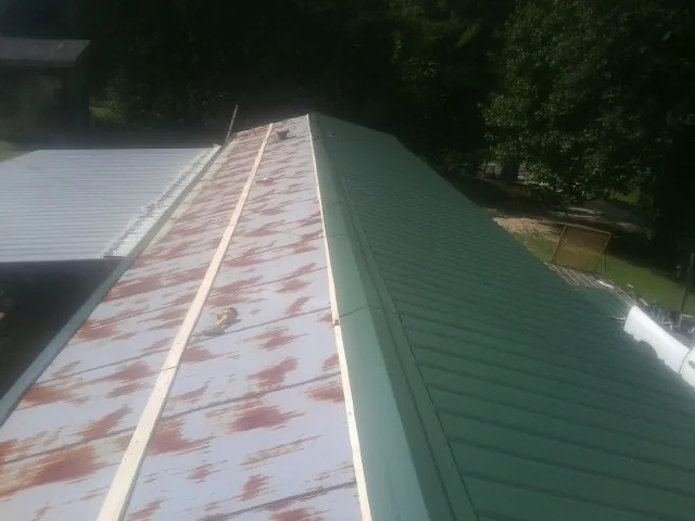 Old rusted panels beside newly installed green metal roofing — Wind Damage Roof Repair by Roofing Brothers in Dunnsville