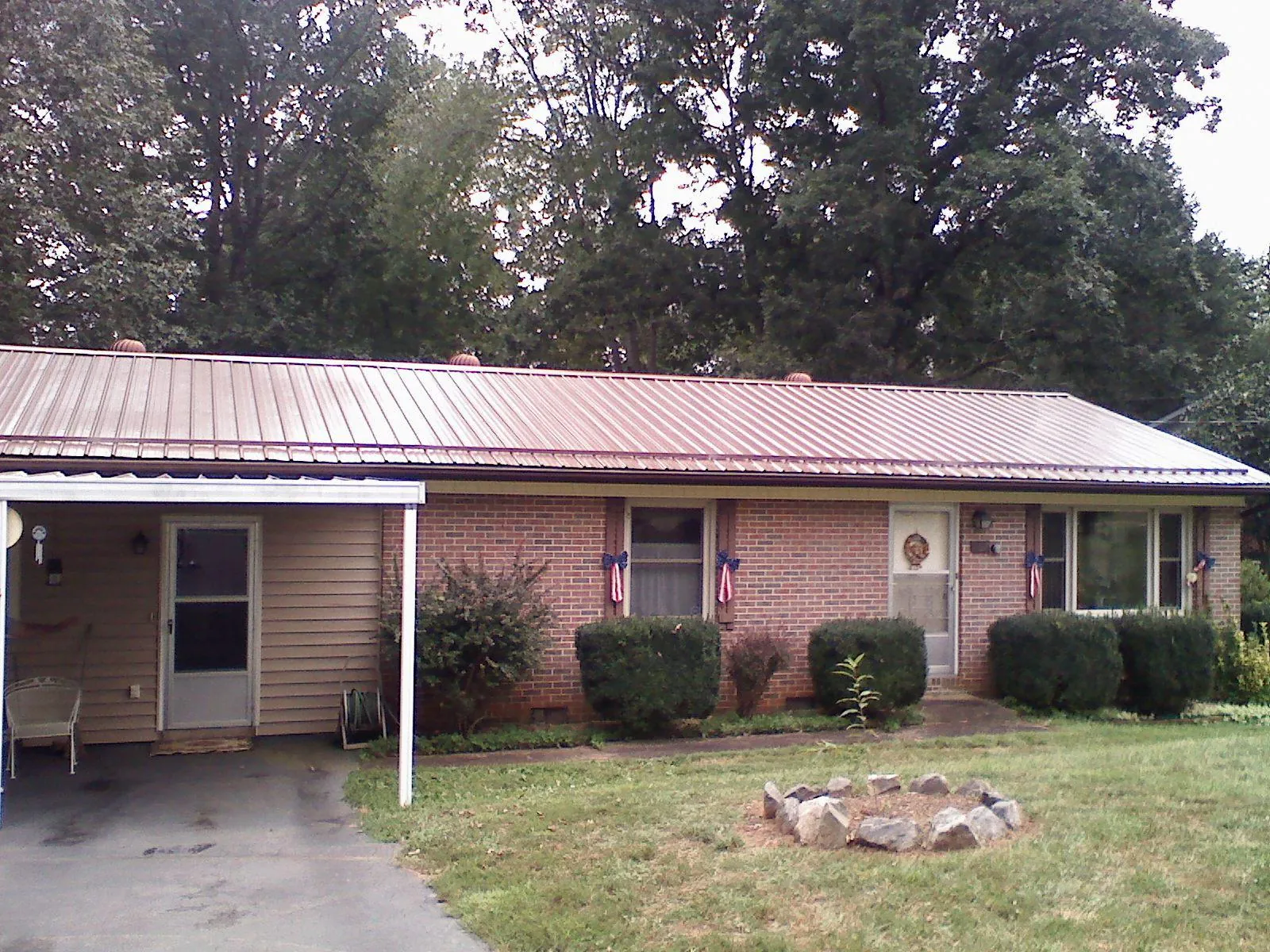 Bronze metal roof and carport on a brick ranch home — Roof Repair work by our crew in Dunnsville