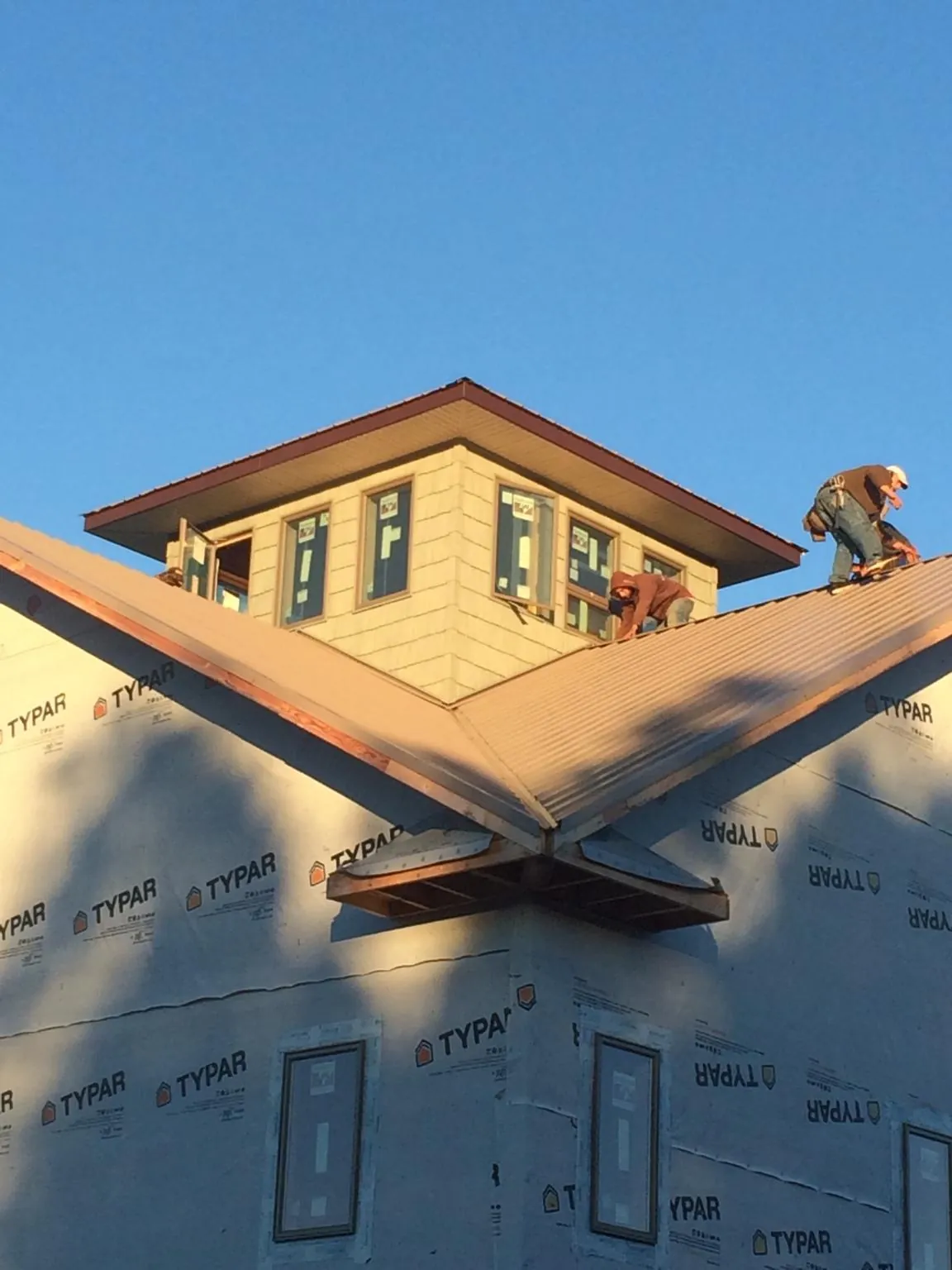 Roofers working around a rooftop cupola on a new metal roof at sunset — Roof Waterproofing in Dunnsville by Roofing Brothers